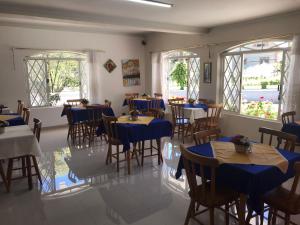um restaurante com mesas e cadeiras azuis e janelas em Pousada Doce Vida em Campos do Jordão