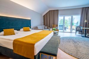 a hotel room with a large bed and a living room at Mazurski Raj - Hotel, Marina & Spa in Ruciane-Nida