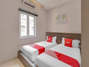 萬隆的住宿－Super OYO Capital O 90726 The Regia Cihampelas Hotel，配有红色和白色床单的客房内的两张床