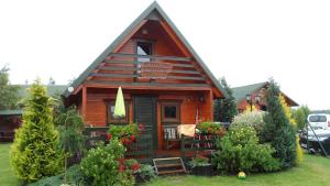 a small log cabin with a porch and some plants at Domki letniskowe Katarzyna in Sarbinowo