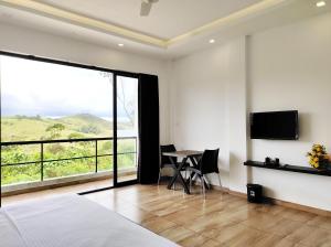 a bedroom with a bed and a table and a large window at Winter Woods in Vagamon