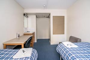 Cette chambre comprend deux lits, un bureau et une table. dans l'établissement LSE Rosebery Hall, à Londres