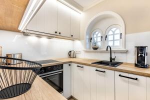 a kitchen with white cabinets and a sink at Ferienhaus Luv in Munkmarsch