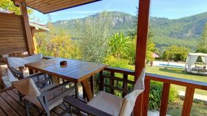 una mesa y sillas en un porche con vistas a las montañas en Lycia Nature House, en Cıralı