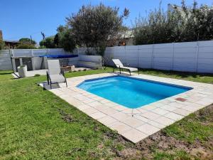 a backyard with a swimming pool with two chairs at Heavenly Breeze in Hermanus