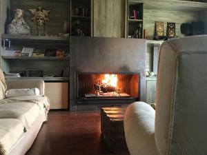 a fireplace in a living room with a fire in it at La Masía de Navas in Navas del Pinar
