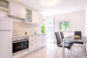 a kitchen with white cabinets and a table and chairs at Holiday Home Villa Frančeska in Postira