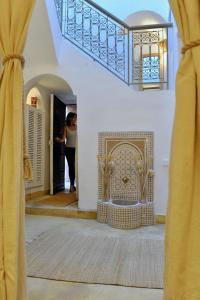 Una donna in piedi in un corridoio vicino a una porta di Riad Dar Jabel a Marrakech