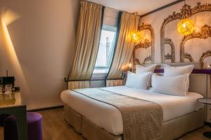 a hotel room with a large bed and a large window at Hotel Yllen Eiffel in Paris