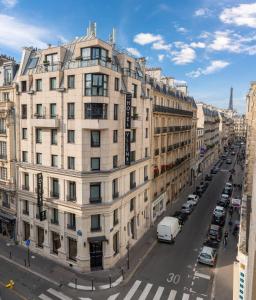 a large white building on a city street with cars at Hotel Yllen Eiffel in Paris