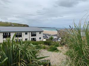 a white building on a beach with the ocean in the background at Beach Apartment, Watergate Bay, Newquay in Newquay