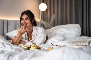 Eine Frau, die mit einem Teller Essen im Bett liegt. in der Unterkunft BAD MOOS - Aqua Spa Resort in Sexten