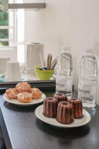 two plates of donuts on a table with water bottles at Hôtel Château La Chèze - Bordeaux Floirac in Floirac