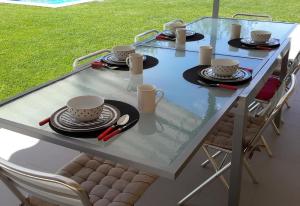 una mesa de cristal con sillas, tazas y platos. en Idyllic guest wing of villa en Sales del Llierca
