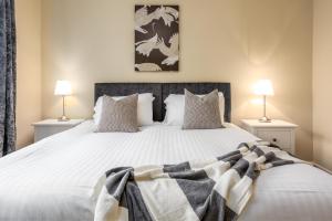 a bedroom with a large white bed with two lamps at The Orchard - Donnini Apartments in Ayr