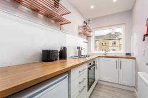 a kitchen with white cabinets and a wooden counter top at The Orchard - Donnini Apartments in Ayr