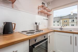 a kitchen with a stove top oven next to a window at The Orchard - Donnini Apartments in Ayr