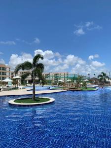a large swimming pool with a palm tree in the middle at Muro Alto condomínio clube in Porto De Galinhas