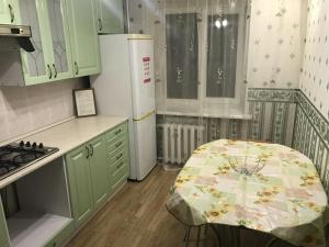TuymazyにあるApartment on Komarova 41のキッチン(緑のキャビネット、テーブル、冷蔵庫付)