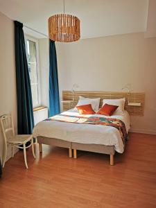 1 dormitorio con 1 cama con cortinas azules y lámpara de araña en Mirabeau en Le Mont-Dore