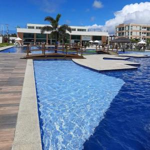 a swimming pool with blue water in front of a building at Muro Alto condomínio clube in Porto De Galinhas