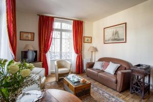 sala de estar con sofá marrón y cortinas rojas en Kereden Location en Saint-Malo