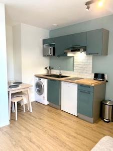 cocina con armarios verdes, mesa y fregadero en LE DUMON 2 - T2 avec GARAGE - TERRASSE - WiFi - Gare à 200m, en Agen