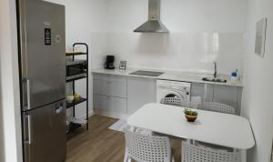 a white kitchen with a table and a refrigerator at Voga Voga in Corcubión