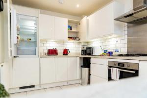 a white kitchen with white cabinets and appliances at Graceful Home Away Sittingbourne 3BH in Kent