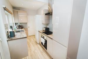 cocina con armarios blancos y fogones en Newly Refurbished House - 10 Minute Walk From City Centre, en Norwich