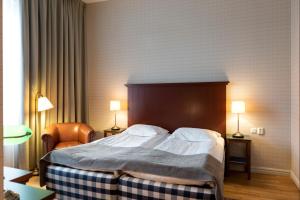 a bedroom with a large bed with a wooden headboard at Hotel Bishops Arms Köping in Köping