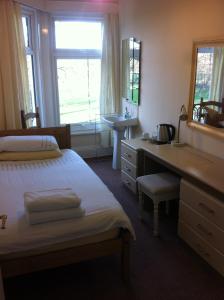 um quarto com uma cama, uma secretária e um lavatório. em Chadwick Guest House em Middlesbrough