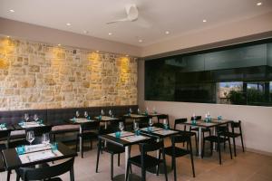 a restaurant with tables and chairs and a stone wall at Hotel Osam - Adults Only in Supetar
