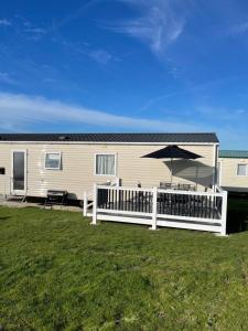 a house with a white fence and an umbrella at Holiday Park Caravan Fluffy in Harts Holiday Park in Leysdown-on-Sea