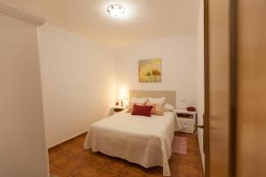 a white bedroom with a white bed and a table at Casa Martina Pampaneira in Pampaneira