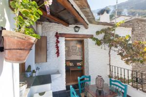 a house with a balcony with a table and chairs at Casa Martina Pampaneira in Pampaneira
