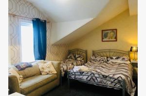 a room with two beds and a couch and a window at Highbury Hotel in Blackpool