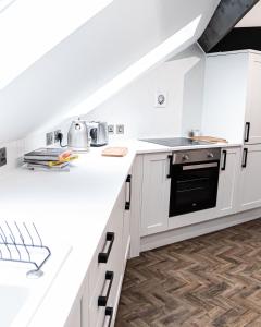 a kitchen with white cabinets and a black oven at Urban Loft Apartment • 1 Bedroom • Manchester in Ashton under Lyne