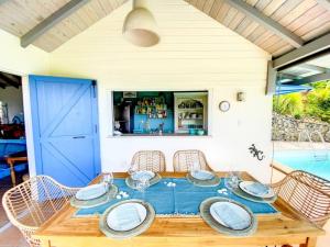 uma mesa de madeira com cadeiras e uma porta azul em Moonstone, private room in Villa Casa Blue pool sea view em Koolbaai