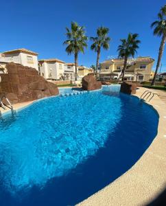 a blue swimming pool with palm trees in the background at Casa Nuez Moscada in Villamartin
