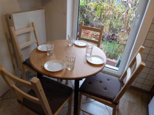 - une table en bois avec des chaises, des assiettes et des verres dans l'établissement ATELIER IM STADTGARTEN 2 direkt in Rottweil, à Rottweil