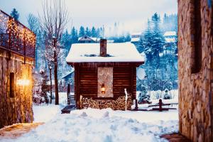 una cabaña de madera en la nieve con luces de Navidad en KLEN Family, en Mykulychyn