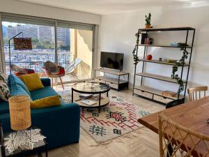 uma sala de estar com um sofá azul e uma mesa em Appartement lumineux 6 places avec vue sur Marina em Mandelieu-la-Napoule