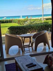 Dawwār ‘Abd al Qādir Qāsim的住宿－شاليه مرقيا بالساحل الشمالي صف اول بحر，一个带桌椅的庭院和海滩