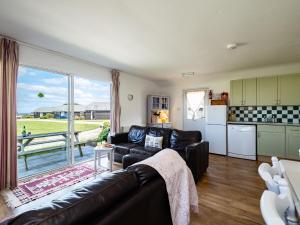 a living room with a leather couch and a kitchen at Atlantic Lodge in Port Isaac