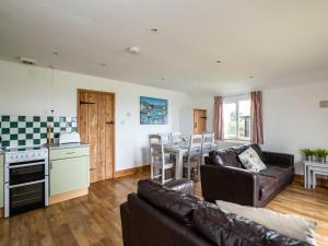 a living room with a couch and a table and a kitchen at Gull Lodge in Port Isaac