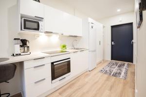 a kitchen with white cabinets and a black door at Apartment Aurinkoranta D8 saunallinen yksiö Kalajoki in Kalajoki