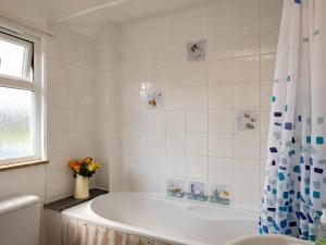 a white bathroom with a tub and a vase of flowers at Harbour Lodge in Port Isaac +30 photos