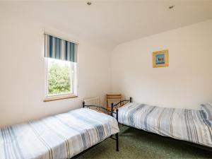 two beds in a white room with a window at Puffin Lodge in Port Isaac