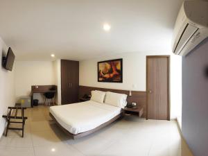 a bedroom with a large white bed and a desk at Hotel Mio Boutique in Cúcuta